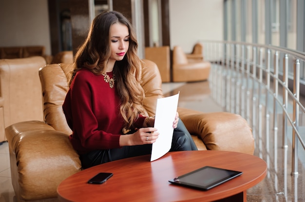 Young businesswoman in a red sweater working with papers