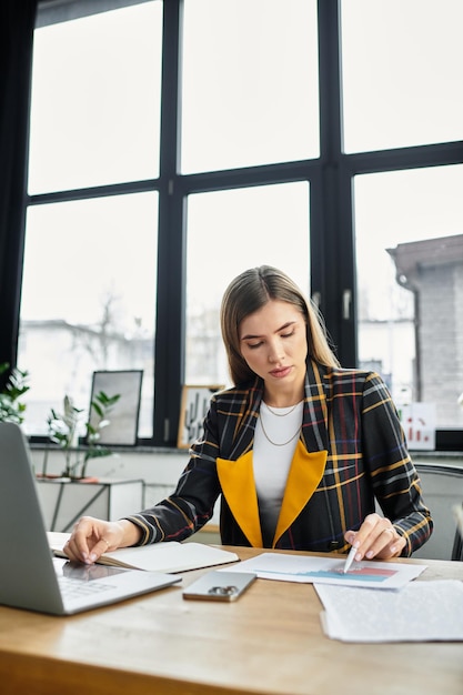 A young businesswoman reviews documents at a sleek office desk focused on her work