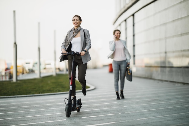 Una giovane donna d'affari che guida uno scooter elettrico mentre va al lavoro.