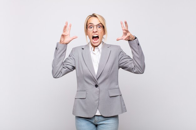 Young businesswoman screaming with hands up in the air, feeling furious, frustrated, stressed and upset