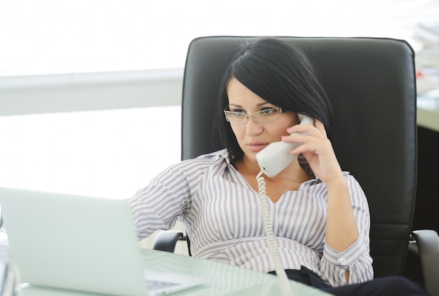 Young businesswoman sitting in an office chair and working