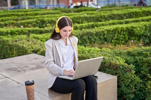 Young businesswoman sitting outside the office with a laptop taking a break or teleworking