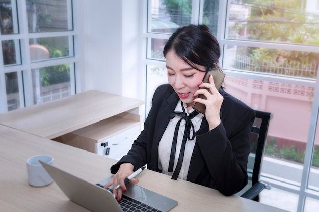 Giovane donna di affari che sorride e che parla con il telefono.