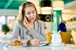 Photo young businesswoman speaking by phone in cafe