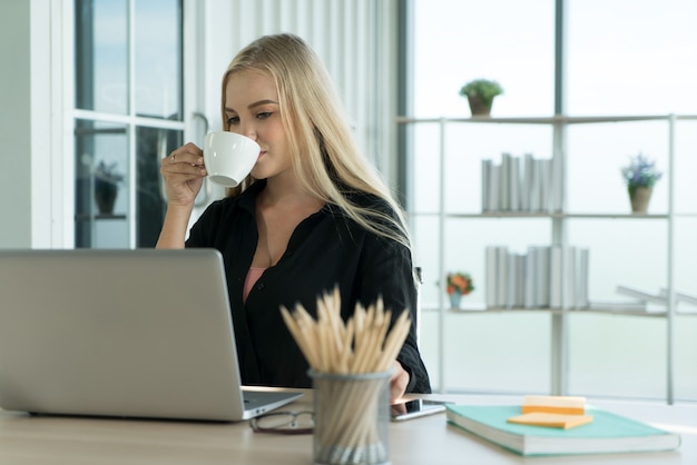 写真 ホームオフィスの机で働いている間コーヒーを飲む若い実業家学生フリーランサー