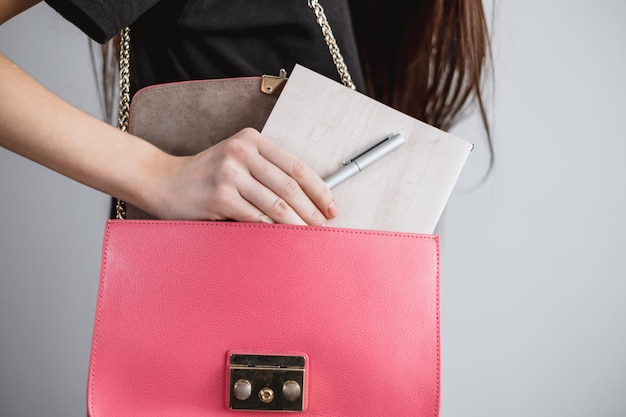 Young businesswoman takes a notebook and pen from her bag