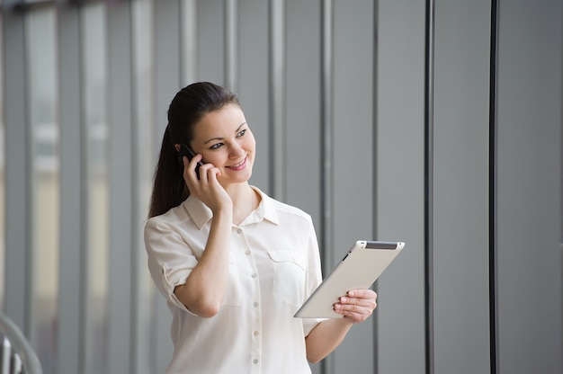 Young businesswoman talking on mobile phone by the window