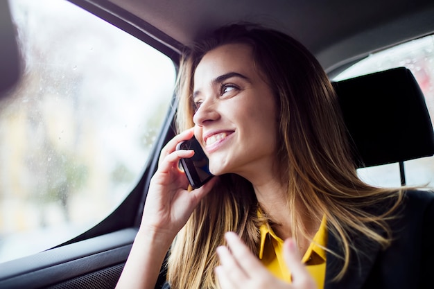 Young businesswoman talking on mobile phone in car