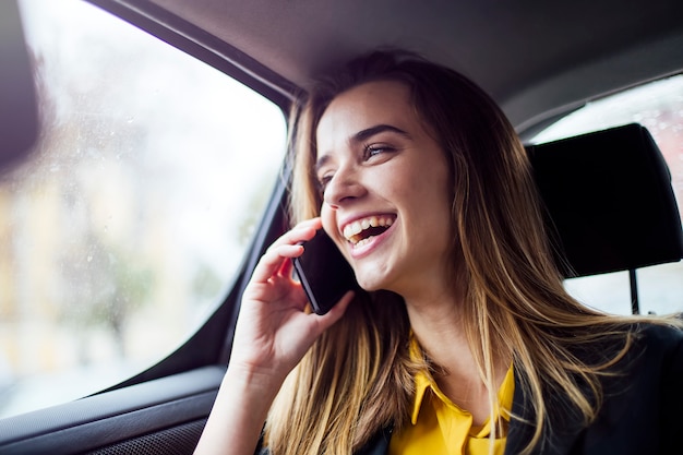 Young businesswoman talking on mobile phone in car