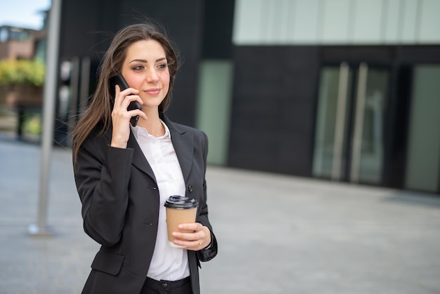 Giovane imprenditrice parlando al telefono in una strada cittadina