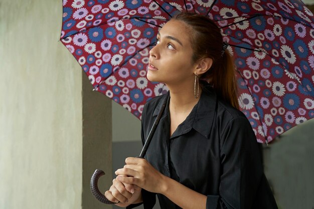 Young businesswoman under umbrella while it is raining outdoors