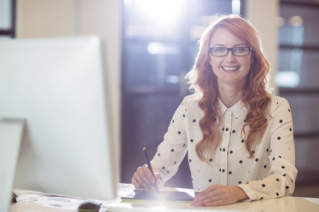 Young businesswoman using graphics tablet at desk