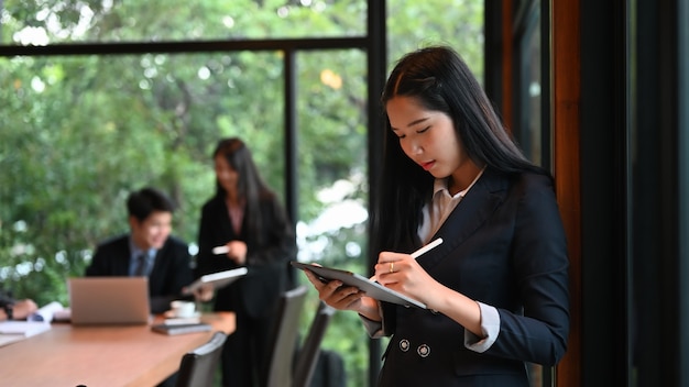 Young businesswoman using stylus pen planing writing her project on tablet in meeting room.