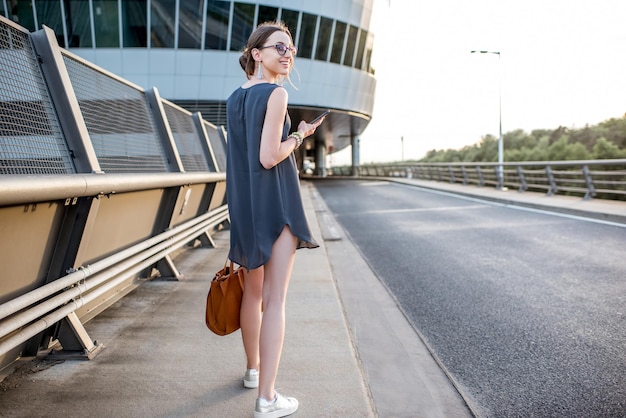 Young businesswoman walking with phone on the highway during the business trip