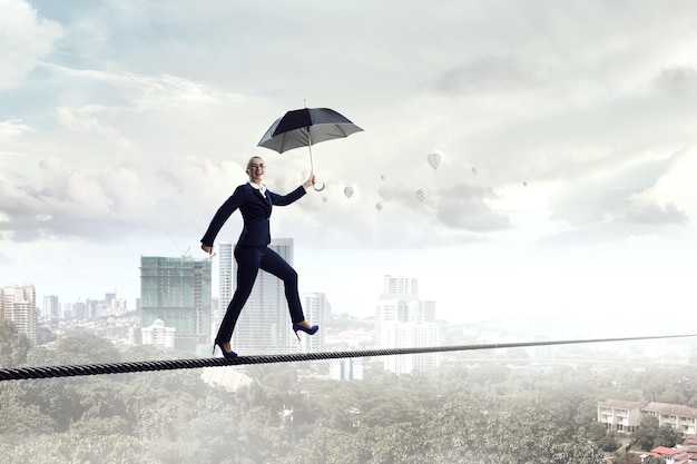 Young businesswoman walking with umbrella. Mixed media