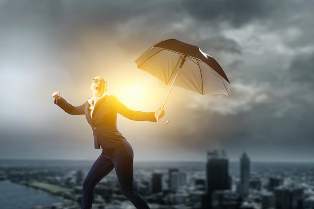 Young businesswoman walking with umbrella. Mixed media