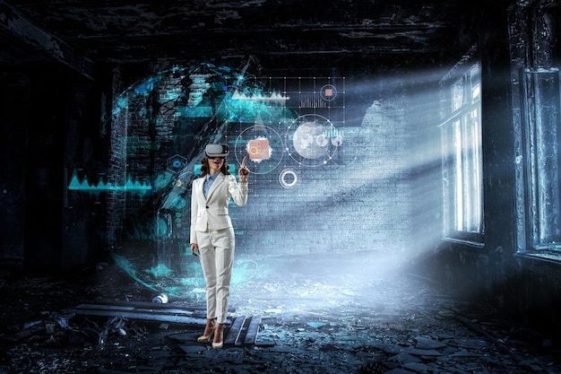 Young businesswoman wearing VR headset working with touch screen. Mixed media