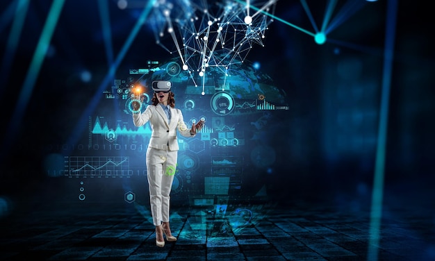 Young businesswoman wearing VR headset working with touch screen. Mixed media