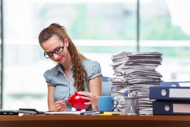 Young businesswoman with piggy bank in the office