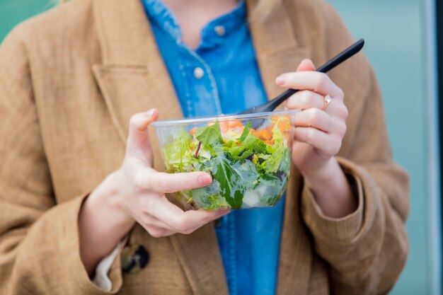 Foto giovane donna di affari con insalata alla città urbana all'aperto.