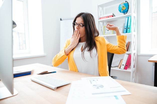 Young businesswoman yawning in office