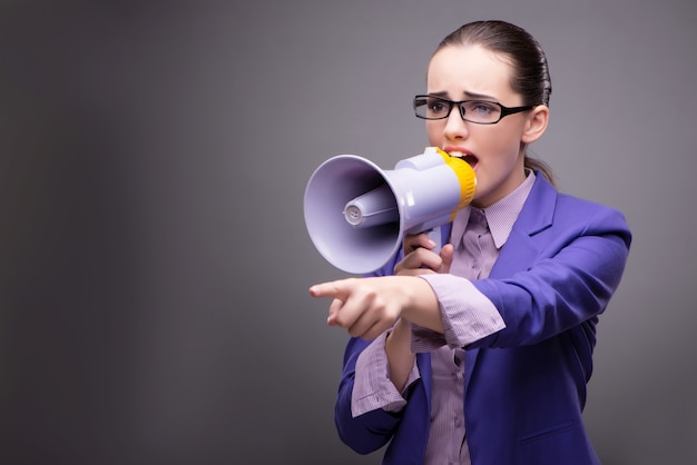 Young businesswoman yelling through loudspeaker