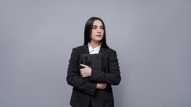 young businesswomen holding book looking right wearing black coat indian pakistani model