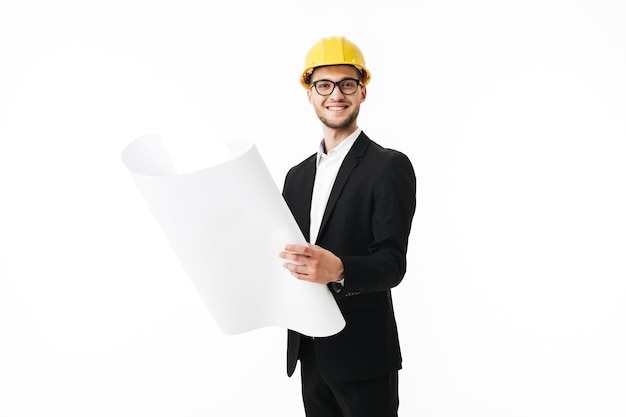 Young bussinesman in eyeglasses and yellow safety helmet happily 