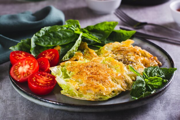 Young cabbage steaks tomatoes and basil on a plate