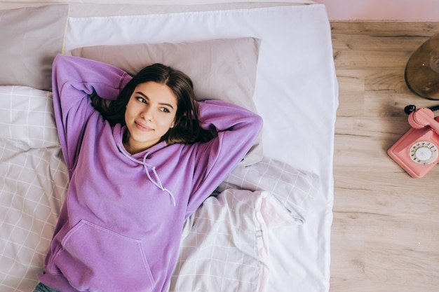 Young calm caucasian woman relaxing lying on comfortable bed in the morning, lazy happy woman resting at home.