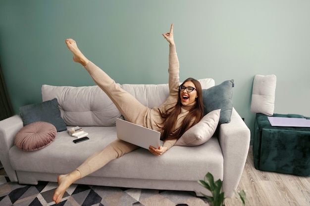 Young calm woman with laptop relaxing sit on comfortable sofa in at home after work, lazy happy  woman girl resting on couch enjoy peace of mind no stress free on couch.  Workplace at hom