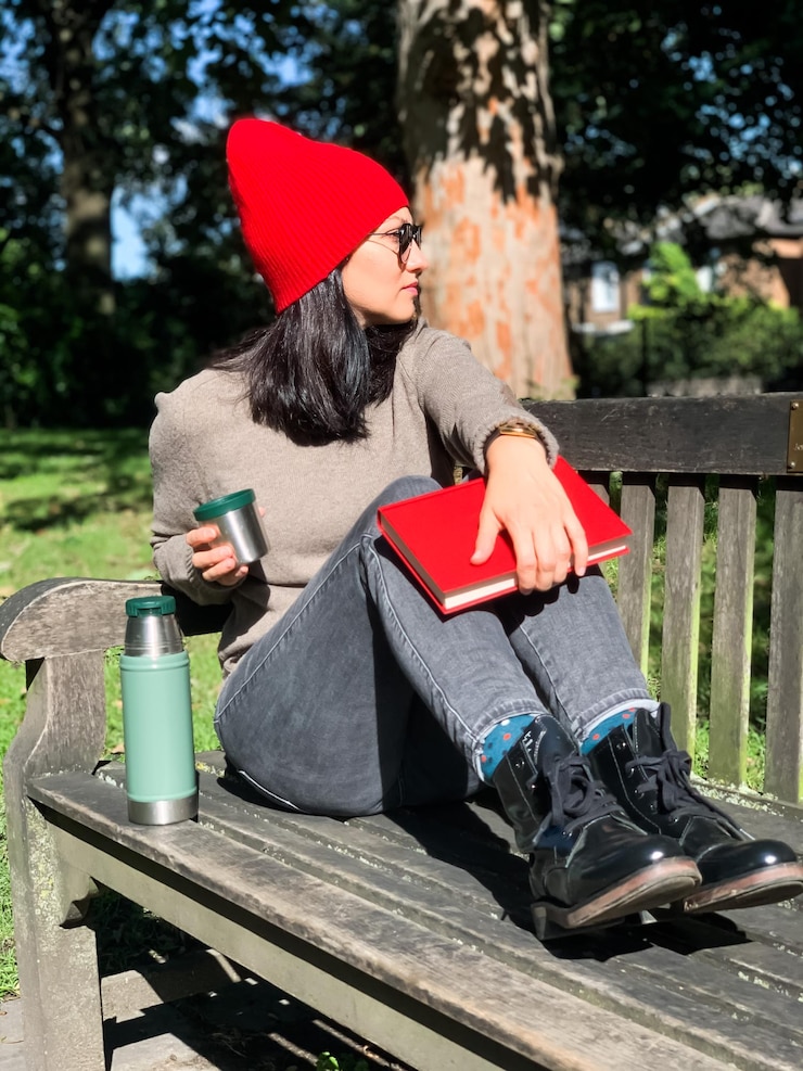 Photo young candid millennial woman in casual autumnal clothes sit on bench drink coffee from  thermos