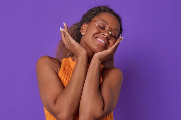 Young carefree african american woman student with glasses touches cheeks