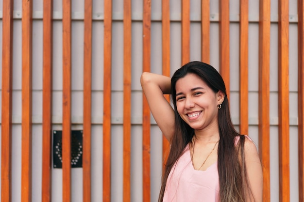 Young and carefree with a cute smile posing with her hands on her head.