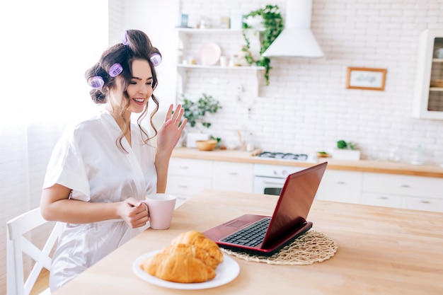 Young carefree woman sitting at table in kitchen