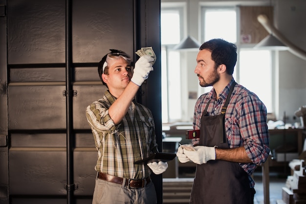 Photo young carpenter gets his money for work in workshop carpentry