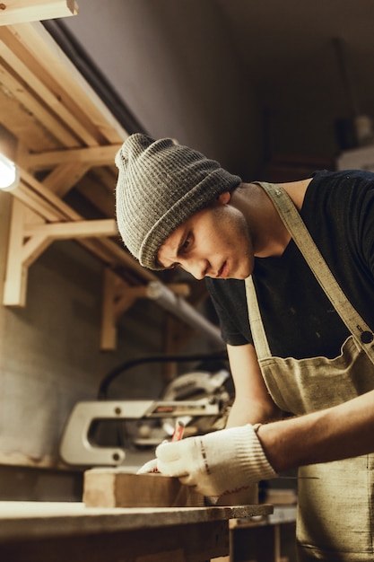 Young carpenter making marks on wood