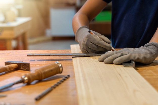 Young carpenter measuring the wood with ruler. 