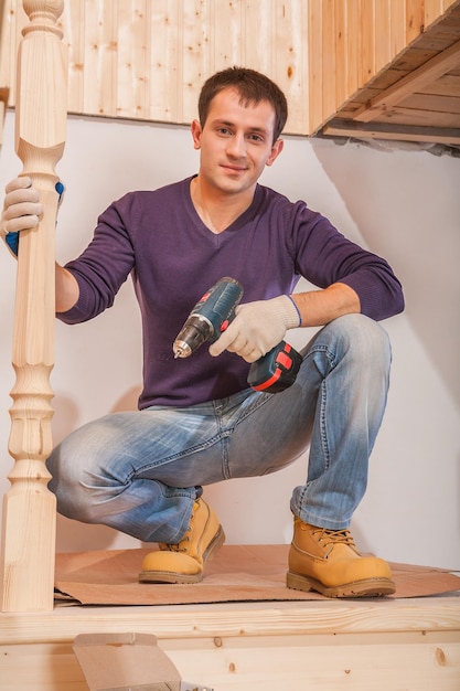 A young carpenter sitting and holding cordless drill