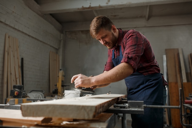 Young carpenter with an apron in his workshop