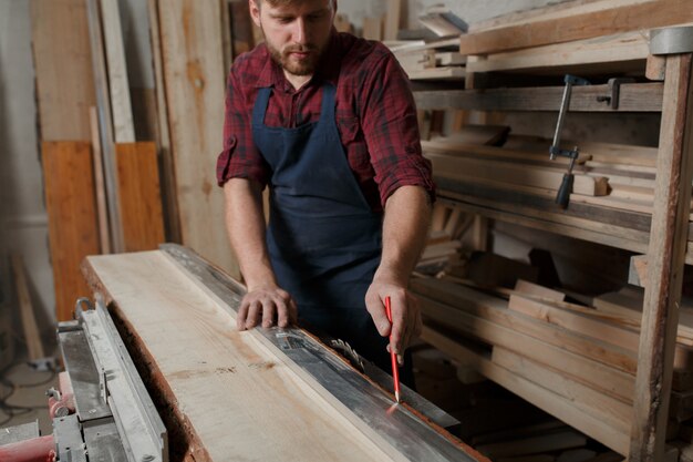 Молодой плотник с фартуком в своей мастерской