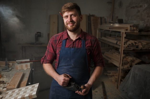 Young carpenter with an apron in his workshop