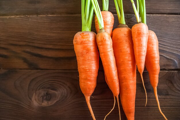 Young carrots with tops on wooden table