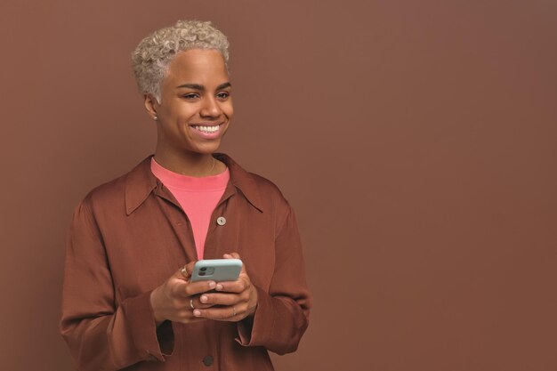 Young casual african american woman zoomer uses mobile phone for online chatting