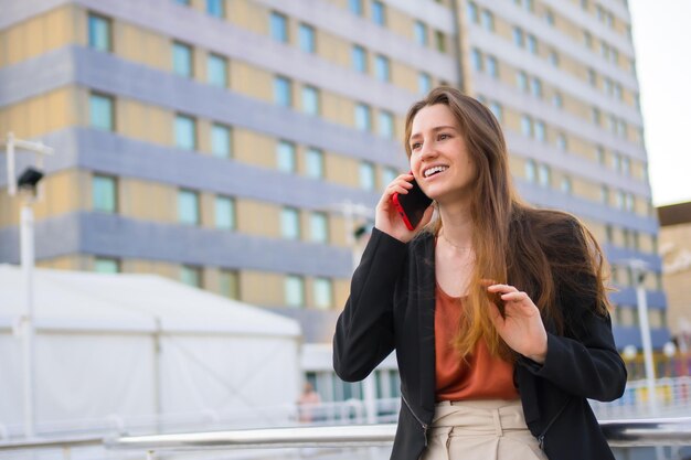 Young and casual businesswoman smiling while talking to the mobile outdoors