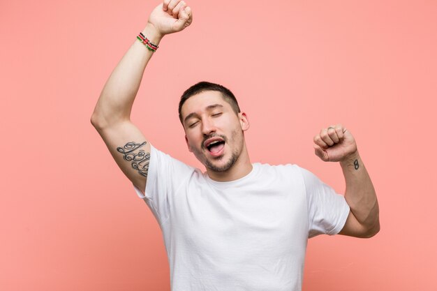 Young casual man celebrating a special day, jumps and raising arms with energy.