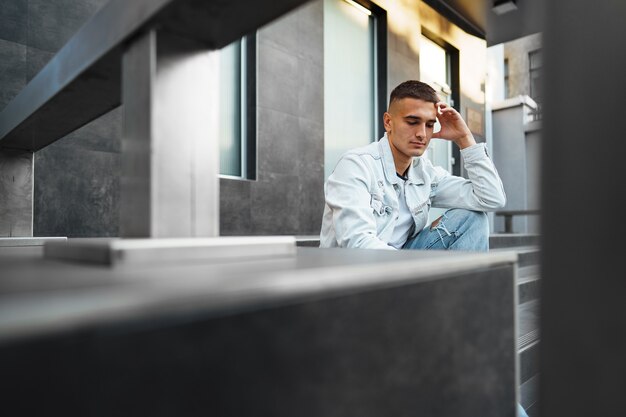 Young casual man sitting on stairs alone on street