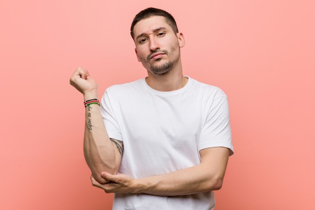 Young casual man touching back of head, thinking and making a choice.