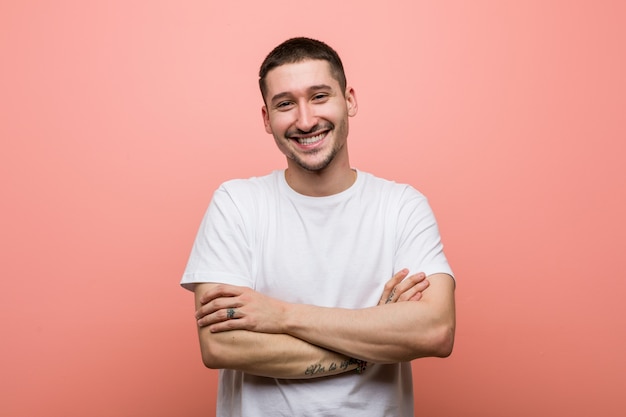 Young casual man who feels confident, crossing arms with determination.