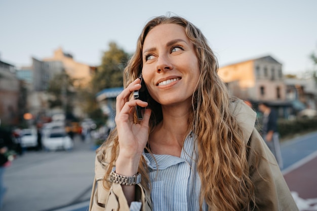 Giovane donna casual che parla sullo smartphone in città